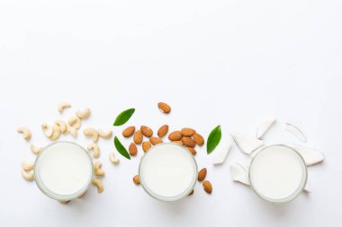 Masa arkasında çeşitli vejetaryen süt bademi, hindistan cevizi, fındık. Vejetaryen bitkisi sütü ve malzemeleri, üst görünüm.