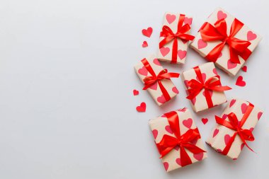 Top view photo of valentine day decorations gift box with red ribbon bow on colored background. Holiday gift boxes with top view.