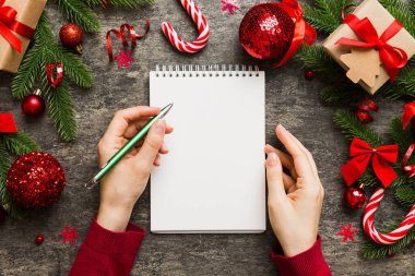 Noel 'i yazmak için bir kadın not defterine Xmas dekorasyonlu renkli arkaplan çiziyor.