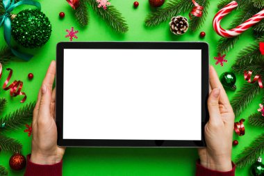 Evden Noel alışverişi, kadın elleri boş beyaz ekranlı tableti tutuyor. Kadın elinde tablet, boş ekran, Noel ağacı ve arka planda hediyeler..