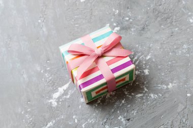 Noel 'i ya da diğer tatil hediyelerini renkli arka planda kurdeleyle renkli kağıda sardım. Şimdiki kutu, renkli tabloda hediye süslemesi, kopya alanı ile üst görünüm.