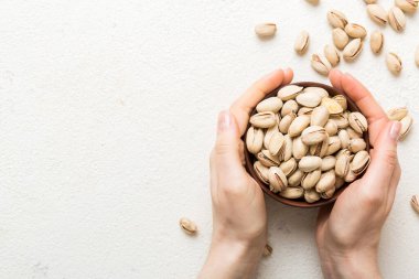Fıstıklı ahşap bir kase tutan kadın elleri. Sağlıklı yemek ve atıştırmalık. Farklı fındıklı vejetaryen atıştırmalıkları..