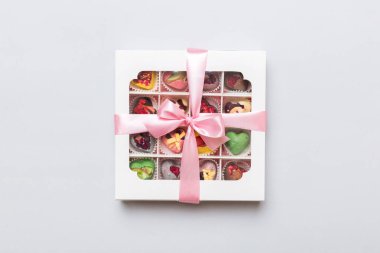 Box with sweet chocolate candies on color background, Various candy sweets. Valentines day gift box. Top view flat lay with copy space.