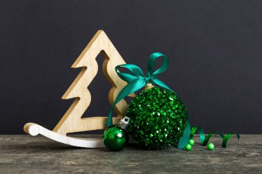 Christmas ball with decorative wooden tree on colored background. decoration bauble with ribbon bow with copy space.