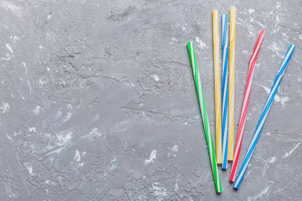 Drinking straws for party on Colored background. Top view of colorful plastic disposable straws for summer cocktails. different straws for juice with copy space.