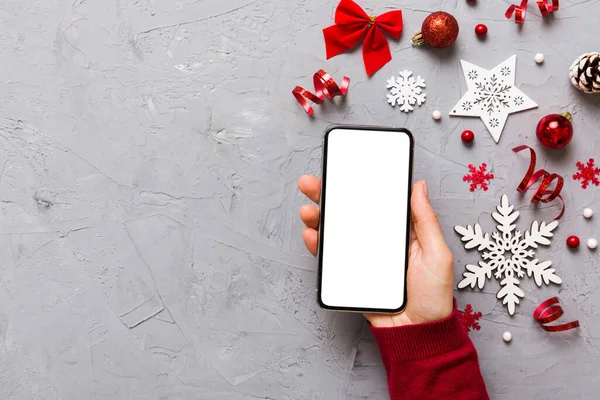 christmas mockup with space for text. christmas advertising, app template. hand holding phone with empty screen on table background. Happy New Year and Xmas Flat lay.