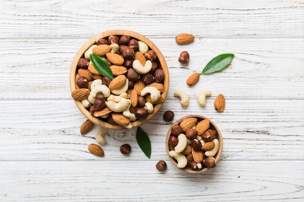 stock image Assortment of nuts in wooden bowl on colored table. Cashew, hazelnuts, walnuts, almonds. Mix of nuts Top view with copy space.