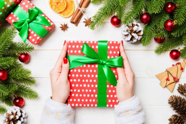 Elinde hediye kutusuyla neşeli tahta arka planda gezen bir kadının en iyi görüntüsü. Firavun ağacı ve Noel süslemeleri. Yeni yıl zaman kavramı.