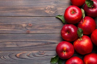 Tahta masada yeşil yapraklı taze kırmızı elmalar. Ahşap arka planda. Metin için üst görünüm boş alanı.