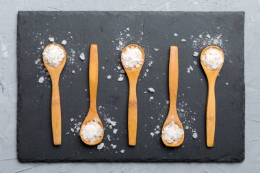 Ahşap arka planda bir sürü tahta kaşıkta tuz. Farklı tuzlu kaşıklar..