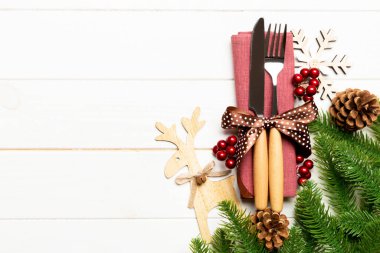 Çatal bıçak takımının en üst görüntüsü ahşap arka planda peçeteyle bağlanmış. Noel süslemeleri ve dizaynınız için boş yeri olan ren geyikleri. Yeni yıl tatili konsepti.