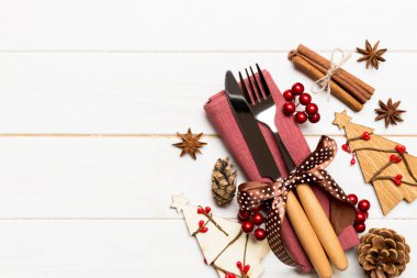 Çatal ve bıçağın üst görüntüsü ahşap arka planda peçeteyle bağlanmış. Noel süsleri ve yılbaşı ağacı. Tasarımınız için boş alanı olan mutlu tatil kavramları.