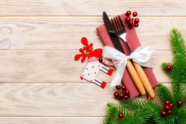 Çatal bıçak takımının en üst görüntüsü ahşap arka planda peçeteyle bağlanmış. Noel süslemeleri ve dizaynınız için boş yeri olan ren geyikleri. Yeni yıl tatili konsepti.