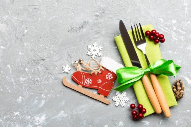 Yeni yıl yemeğinin çimento arka planındaki en iyi görüntüsü. Noel süslemeleri ve oyuncaklarıyla peçetenin üzerindeki şenlikli çatal bıçak takımı. Fotokopi alanı olan aile tatili kavramı.