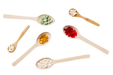 Renkli arka planda tahta kaşıkta vitamin ve mineral haplarının üst görünümü. Muhtelif ilaç haplarının en üst görüntüsü. Beslenme takviyesi sağlık ürünleri.