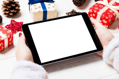 Hediye kutularından yapılmış ahşap Noel arka planında bir tablet tutan kadınların üst görüntüsü. Yeni yıl tatili konsepti. Model.