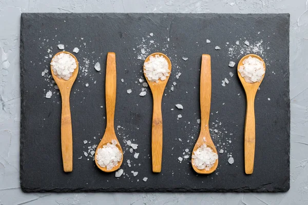 Ahşap arka planda bir sürü tahta kaşıkta tuz. Farklı tuzlu kaşıklar..
