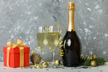 Champagne bottle with confetti, glasses and christmas decor on colored holiday background. Flat lay New Year decorations.