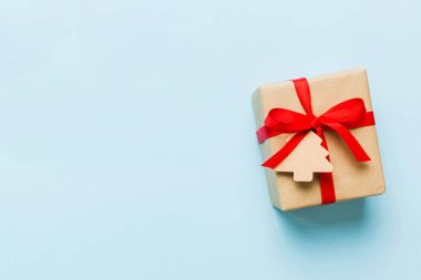 wrapped christmas or other holiday handmade present in paper with colored ribbon. Present box, decoration of gift on colourfull table, top view with copy space.