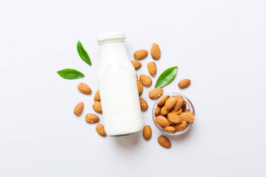Cam şişedeki badem sütü ve renkli masada badem fıstığı. Üst görünüm vith kopyalama alanı.