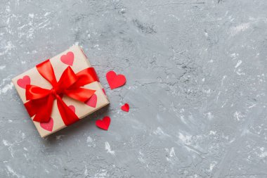 Top view photo of valentine day decorations gift box with red ribbon bow on colored background. Holiday gift boxes with top view.
