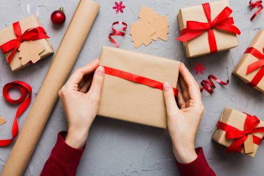 Kadınlar Noel tatili için sürpriz hediyeler hazırlıyor. İş yerinde el aletleri ve manzarayla oturuyor. Renkli masada Noel hediyesini paketleyen kadın..