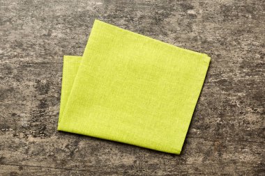 top view with green kitchen napkin isolated on table background. Folded cloth for mockup with copy space, Flat lay. Minimal style.