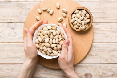 Fıstıklı ahşap bir kase tutan kadın elleri. Sağlıklı yemek ve atıştırmalık. Farklı fındıklı vejetaryen atıştırmalıkları..