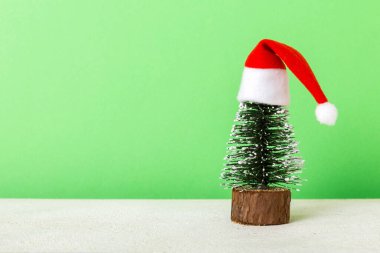 One small Christmas tree with santa hat on colored background. new year decoration with copy space.