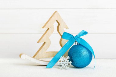 Christmas ball with decorative wooden tree on colored background. decoration bauble with ribbon bow with copy space.