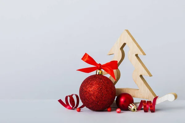 Christmas ball with decorative wooden tree on colored background. decoration bauble with ribbon bow with copy space.
