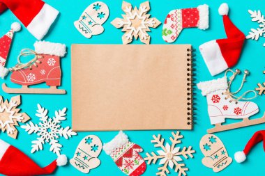 Noel süsleri ve mavi arka planda Noel Baba şapkaları olan defterin üst görüntüsü. İyi bayramlar..