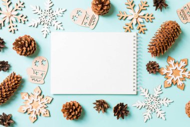 Not defterinin en üst görüntüsü, tatil oyuncakları ve mavi Noel arkaplanındaki süslemeler. Yeni yıl konsepti.