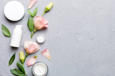 Kozmetik ürünleri ve çimento arka planında güzel güller olan kompozisyon. Uzayı kopyala, düz yat.