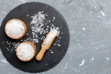 Ahşap bir arka planda ahşap bir kase tuz kristali. Kırsal kaselerdeki tuz, fotokopi alanı olan üst görünüm.