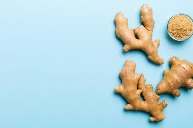 Renkli arka planda yeşil yapraklı kabın içinde zencefil tozu var. Üst görünüm düzlüğü.