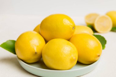 Taze kesilmiş limon ve tüm limonları renkli arka planda yuvarlak tabakta. Yemek ve içecek malzemeleri hazırlanıyor. Sağlıklı beslenme teması üst görünüm kopyalama alanı.