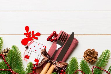 Çatal bıçak takımının en üst görüntüsü ahşap arka planda peçeteyle bağlanmış. Noel süslemeleri ve dizaynınız için boş yeri olan ren geyikleri. Yeni yıl tatili konsepti.