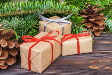 Noel ağacı dalı, süslemeleri ve hediye kutusu beyaz ahşap masa üzerinde.