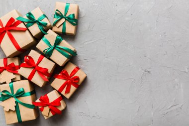 wrapped christmas or other holiday handmade present in paper with colored ribbon. Present box, decoration of gift on colourfull table, top view with copy space.