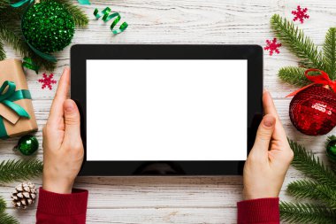 Evden Noel alışverişi, kadın elleri boş beyaz ekranlı tableti tutuyor. Kadın elinde tablet, boş ekran, Noel ağacı ve arka planda hediyeler..