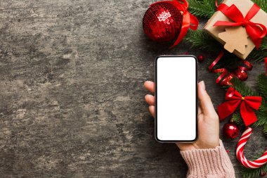 Mesaj atmak için yeri olan bir Noel modeli. Noel reklamı, uygulama şablonu. Masa arkasında boş ekran olan el ele tutuşan telefon. Mutlu yıllar ve Xmas Flat.