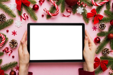 Evden Noel alışverişi, kadın elleri boş beyaz ekranlı tableti tutuyor. Kadın elinde tablet, boş ekran, Noel ağacı ve arka planda hediyeler..