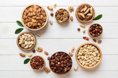 mixed nuts in wooden bowl. Mix of various nuts on colored background. pistachios, cashews, walnuts, hazelnuts, peanuts and brazil nuts.