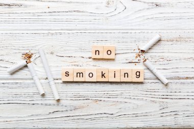 Sigara ve tahta bloklar, masa arkasında kırık sigara kum saati ile tütün günü yok, saat sağlığı konsepti. Sigarayı bırakma zamanı..