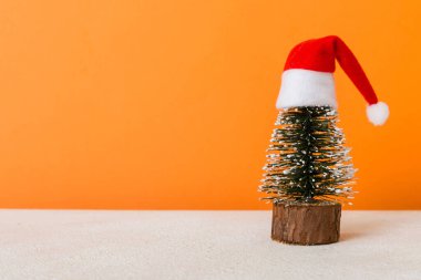 One small Christmas tree with santa hat on colored background. new year decoration with copy space.