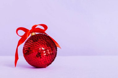 Christmas ball on colored background. decoration bauble with ribbon bow with copy space.