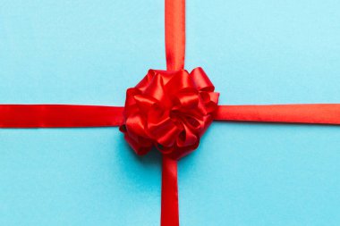 Kırmızı kurdelenin üst görüntüsü yuvarlandı ve kırmızı fiyonk renkli arka planda izole edildi. Kopyalama alanı olan düz.