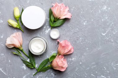 Kozmetik ürünleri ve çimento arka planında güzel güller olan kompozisyon. Uzayı kopyala, düz yat.