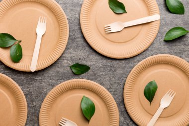 Açık beyaz masa arkaplanındaki boş, tek kullanımlık çevre dostu tabaklar, bardaklar, çatal bıçaklar. Üst Manzara. Biyo-çözünebilir el yapımı yemekler. Geri dönüşüm konsepti. Yakın plan..